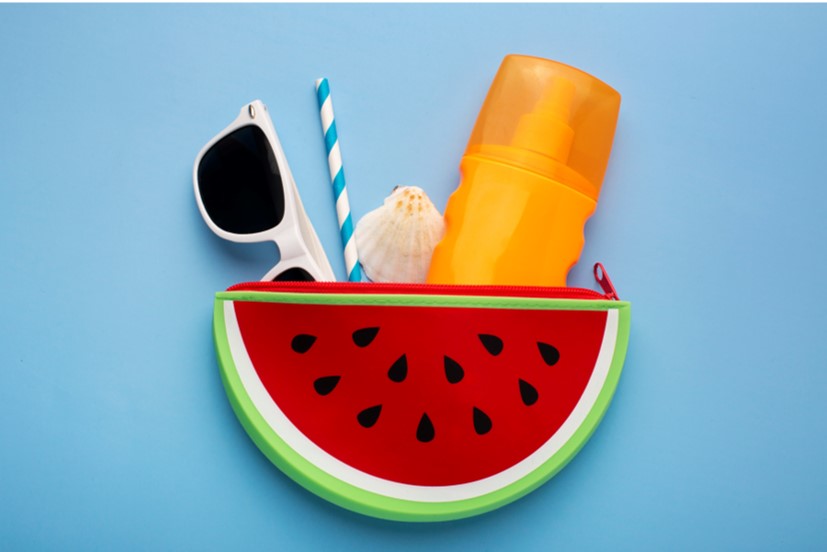 watermelon shaped case filled with sunglasses, a straw, seashell and sunscreen